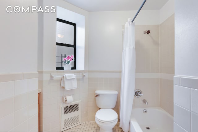 305 W 143rd St Unit 2, New York City, NY 10030 - bathroom with radiator, tile walls, shower / bath combo with shower curtain, a wainscoted wall, and tile patterned floors
