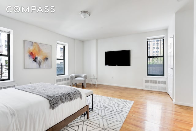 305 W 143rd St Unit 2, New York City, NY 10030 - bedroom with radiator, light wood-type flooring, and multiple windows
