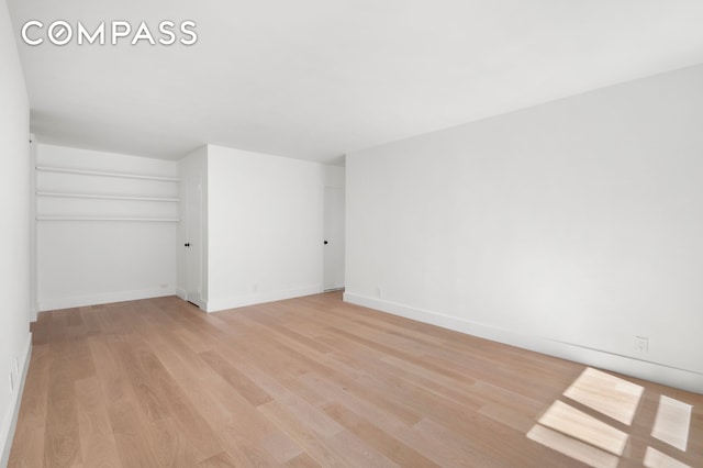 unfurnished room with light wood-type flooring and baseboards