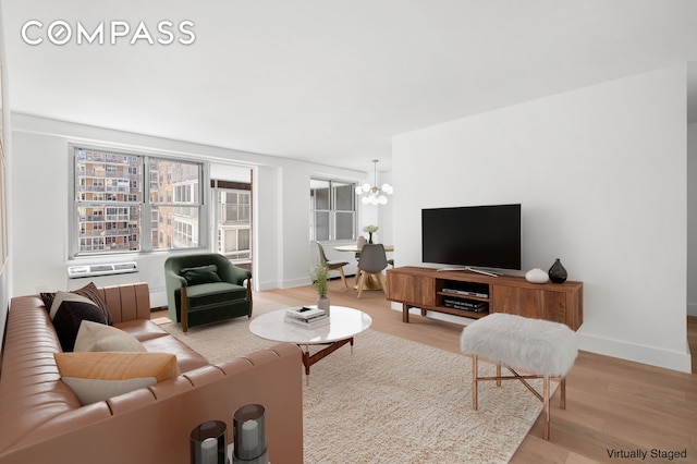living area featuring baseboards, light wood finished floors, and a notable chandelier