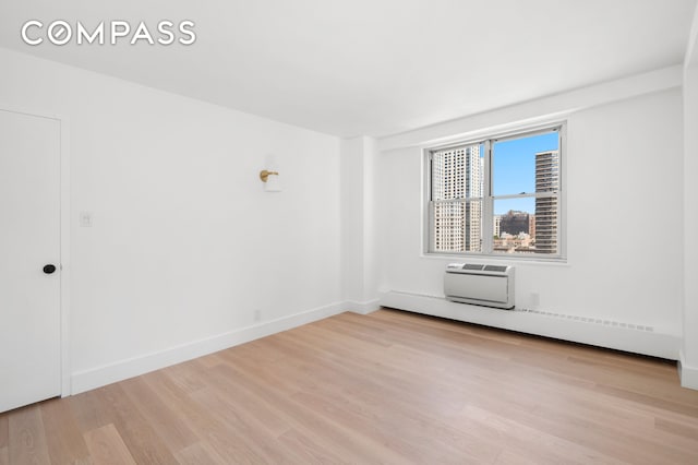 unfurnished room featuring light wood-style floors, baseboards, a baseboard heating unit, and a wall mounted air conditioner
