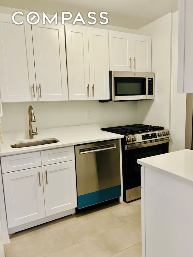 kitchen with a sink, appliances with stainless steel finishes, white cabinets, and light countertops