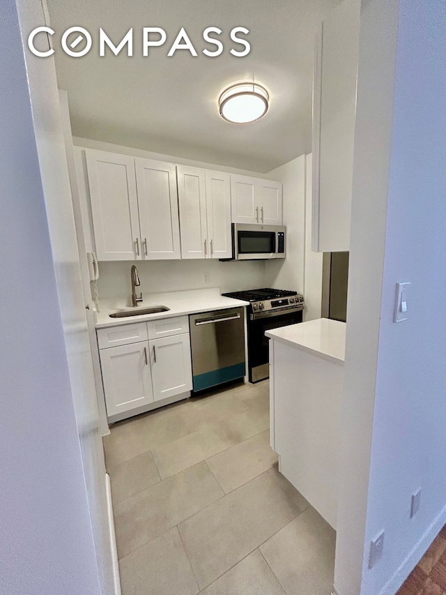 kitchen with a sink, appliances with stainless steel finishes, white cabinets, and light countertops
