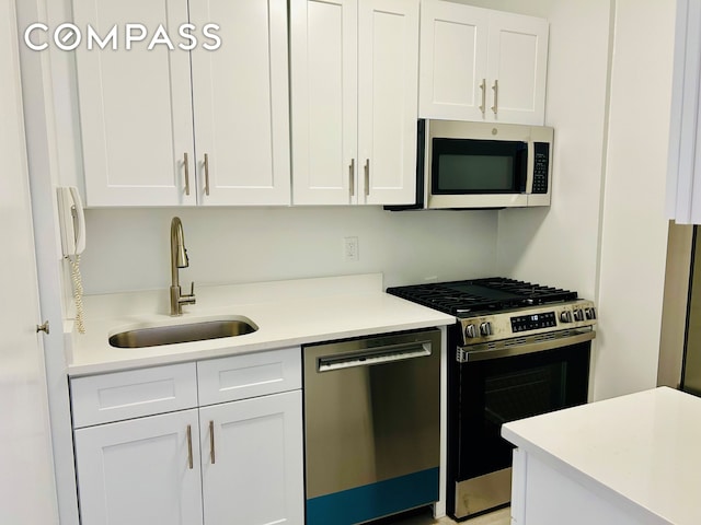 kitchen featuring light countertops, a sink, white cabinets, and stainless steel appliances