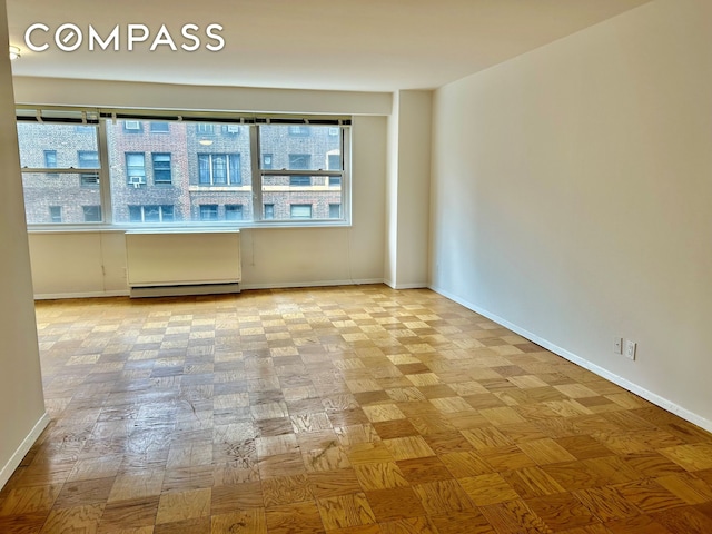 unfurnished room featuring baseboards, a baseboard heating unit, and a wealth of natural light