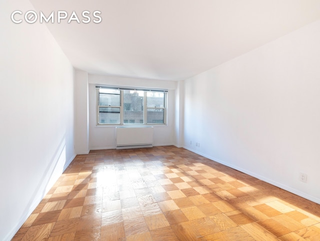 unfurnished room featuring baseboards and radiator