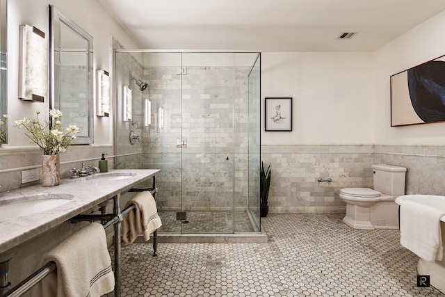 bathroom featuring tile patterned floors, tile walls, visible vents, and a stall shower