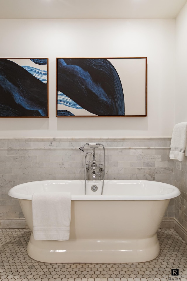 bathroom with tile patterned floors, tile walls, wainscoting, and a soaking tub
