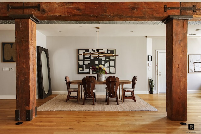 dining area featuring light wood-style floors, baseboards, an inviting chandelier, and beamed ceiling