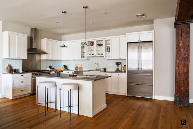 kitchen with premium appliances, visible vents, dark countertops, and wall chimney exhaust hood