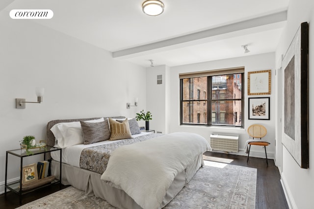 bedroom with baseboards, a wall unit AC, wood finished floors, and visible vents