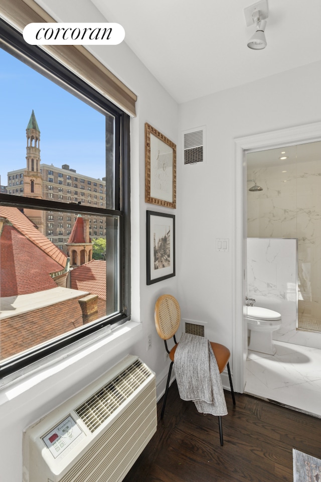 sitting room with visible vents, a city view, baseboards, and wood finished floors