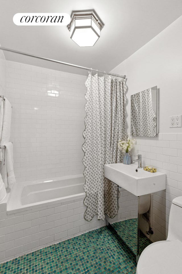 bathroom with tile patterned floors, tiled shower / bath, toilet, and tile walls