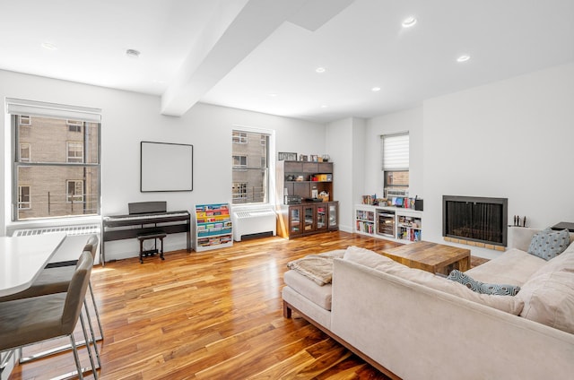 living room with a healthy amount of sunlight, baseboards, radiator heating unit, and wood finished floors