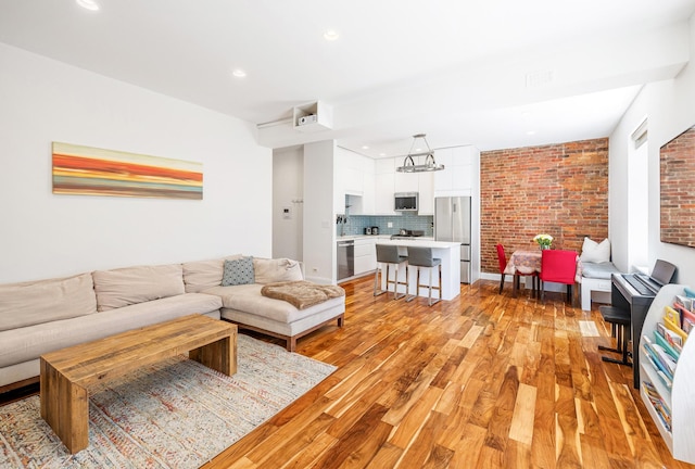 living area featuring recessed lighting, light wood finished floors, and brick wall