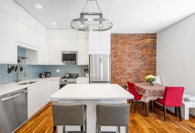 kitchen with a kitchen island, modern cabinets, a sink, white cabinets, and stainless steel appliances