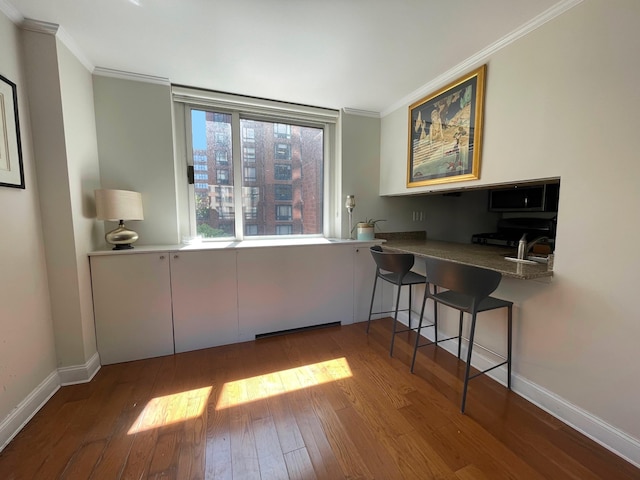 dining area with crown molding, baseboards, and hardwood / wood-style floors