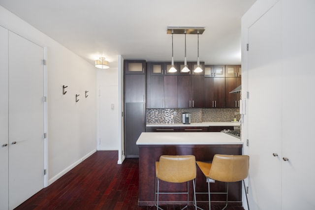 60 E 8th St Unit 11D, New York City, NY 10003 - kitchen featuring dark brown cabinetry, light countertops, dark wood finished floors, decorative backsplash, and glass insert cabinets