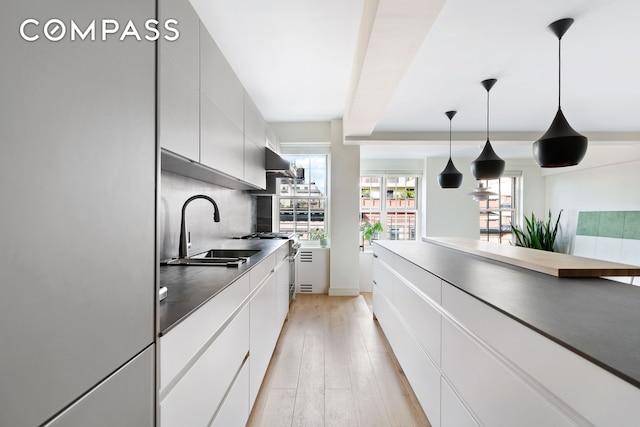 320 W 76th St Unit 7De, New York City, NY 10023 - kitchen featuring a sink, stainless steel fridge, light wood-style flooring, white cabinets, and modern cabinets