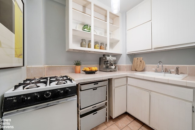 54 Orange St Unit 5D, New York City, NY 11201 - kitchen featuring white gas range, a sink, white cabinets, light tile patterned floors, and tile countertops
