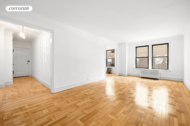 unfurnished room with visible vents, baseboards, and radiator heating unit