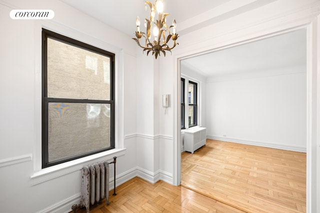 empty room with radiator, visible vents, baseboards, and a notable chandelier