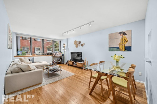 living area featuring baseboards, track lighting, and light wood-type flooring