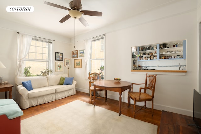 living area with ceiling fan, visible vents, and baseboards