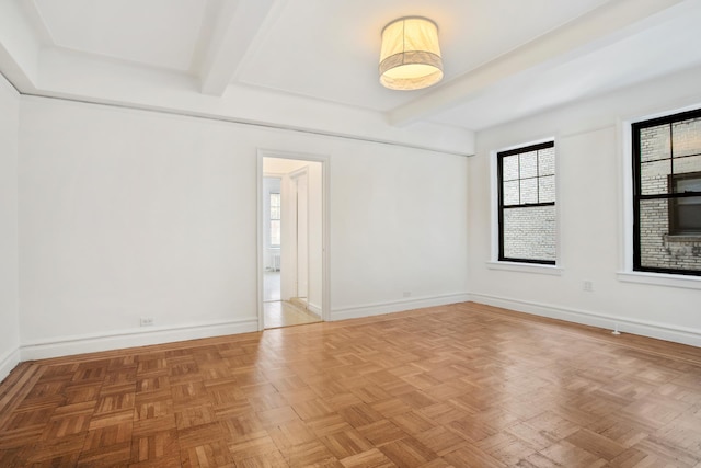 empty room featuring baseboards and beam ceiling