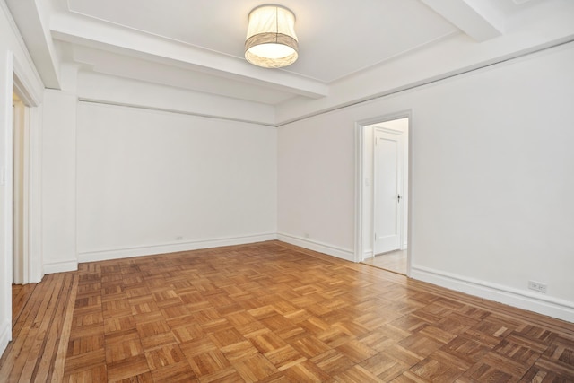 spare room with baseboards and beam ceiling