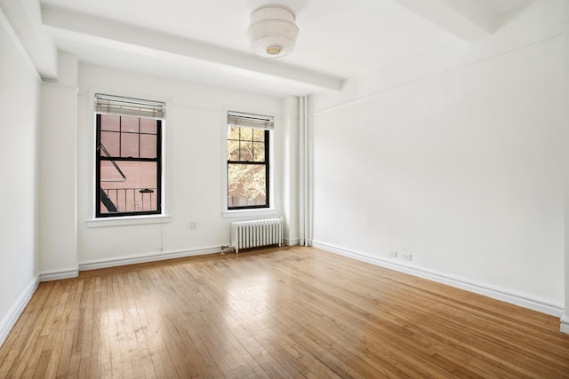spare room featuring light wood-type flooring, baseboards, and radiator heating unit