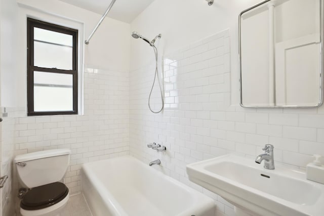 full bath featuring a sink, tile walls, washtub / shower combination, and toilet