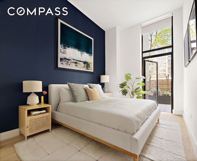 bedroom featuring access to outside, baseboards, and wood finished floors