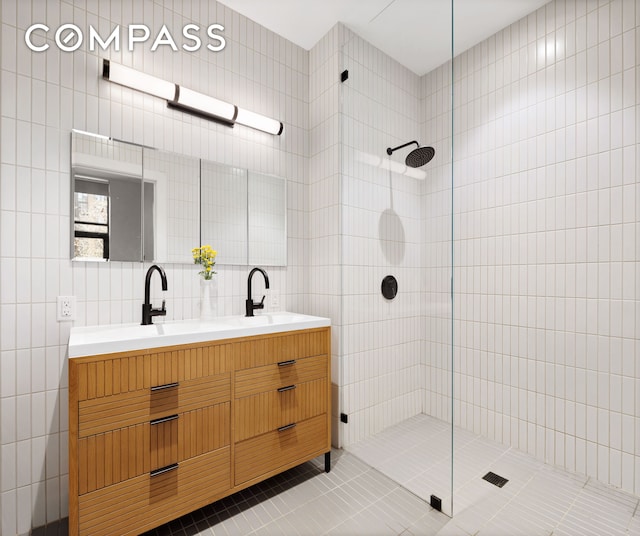 bathroom featuring double vanity, tile walls, tile patterned flooring, walk in shower, and a sink