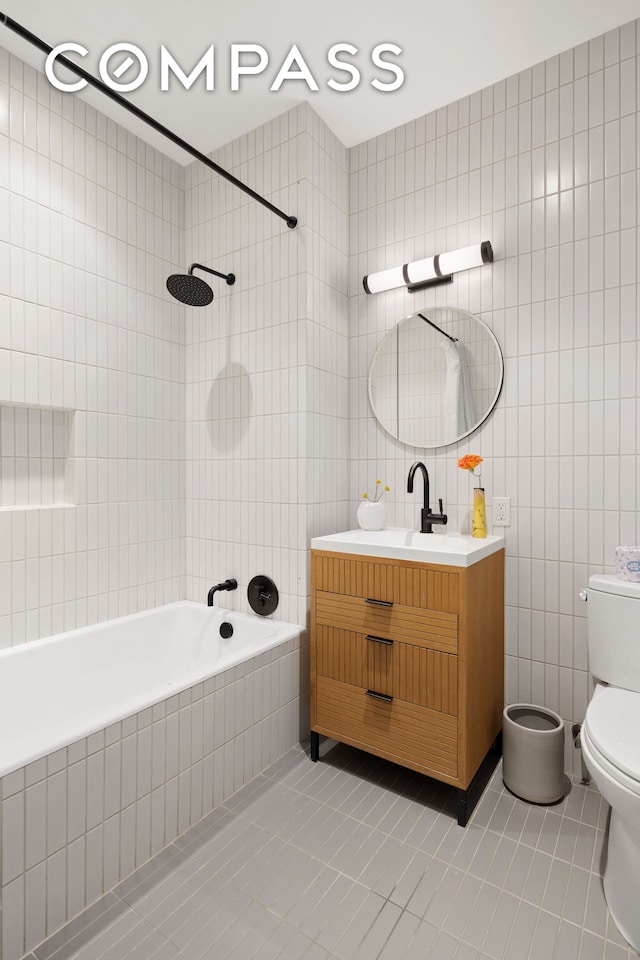 full bath featuring tile walls, tile patterned flooring, vanity, toilet, and tiled shower / bath combo