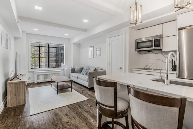 45 Tudor City Pl Unit 507, New York City, NY 10017 - kitchen with radiator, stainless steel microwave, white cabinetry, a sink, and pendant lighting