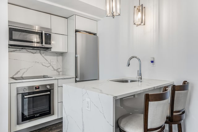 45 Tudor City Pl Unit 507, New York City, NY 10017 - kitchen featuring appliances with stainless steel finishes, a sink, white cabinets, modern cabinets, and light stone counters
