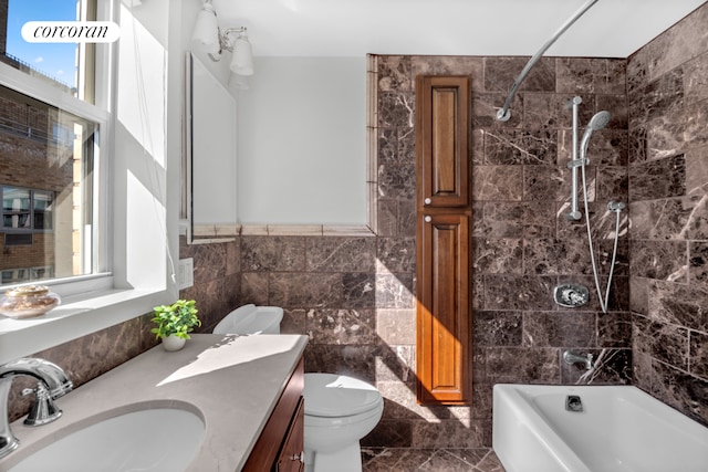 bathroom featuring vanity, marble finish floor, washtub / shower combination, and tile walls