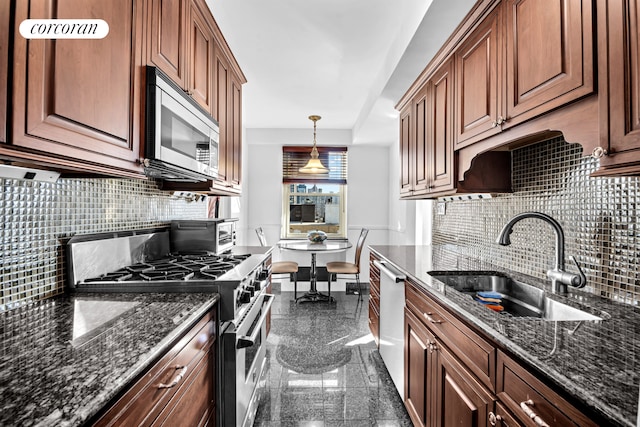 kitchen with appliances with stainless steel finishes, a sink, granite finish floor, dark stone counters, and decorative backsplash