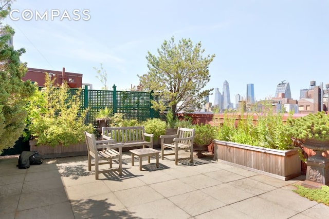 view of patio / terrace featuring fence and a city view
