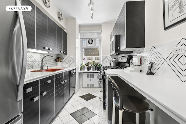 kitchen with dark cabinets, a sink, appliances with stainless steel finishes, and light countertops