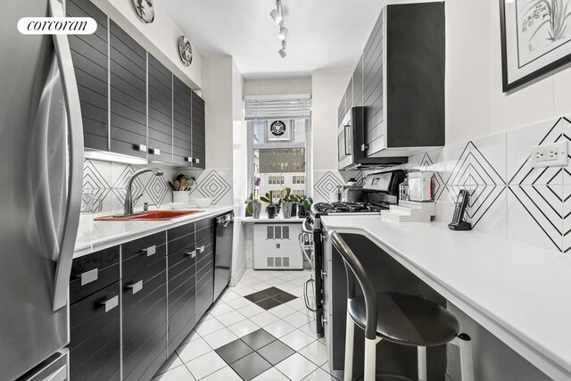 200 E 57th St Unit 14F, New York City, NY 10022 - kitchen with stainless steel appliances, dark cabinetry, light countertops, and tasteful backsplash