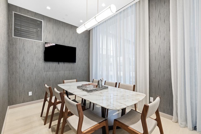 dining room featuring baseboards, light wood-style flooring, and wallpapered walls