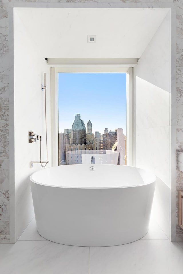 full bath featuring a view of city, marble finish floor, and a soaking tub