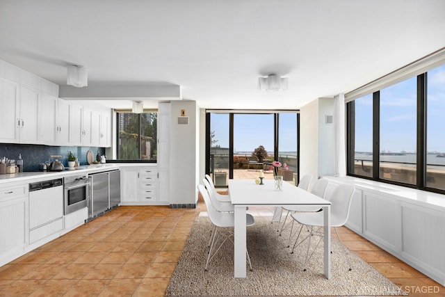 kitchen with white cabinets, dishwasher, light countertops, stainless steel oven, and decorative backsplash
