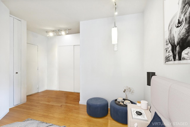 bedroom with rail lighting and wood finished floors