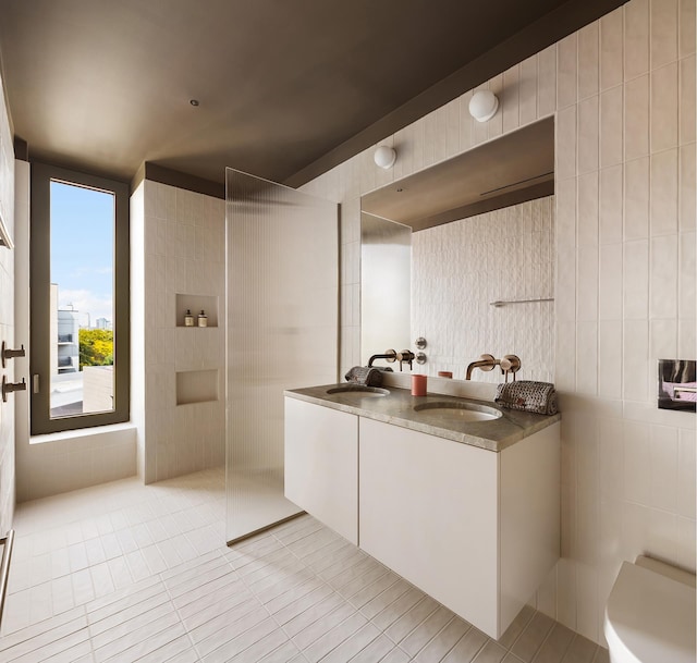 bathroom featuring double vanity, a sink, a walk in shower, and tile patterned floors
