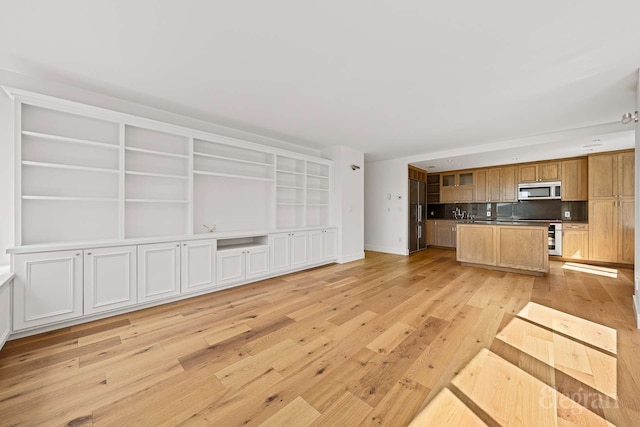 333 Rector Pl Unit 805, New York City, NY 10280 - kitchen with stainless steel microwave, open floor plan, light wood-type flooring, a center island with sink, and baseboards