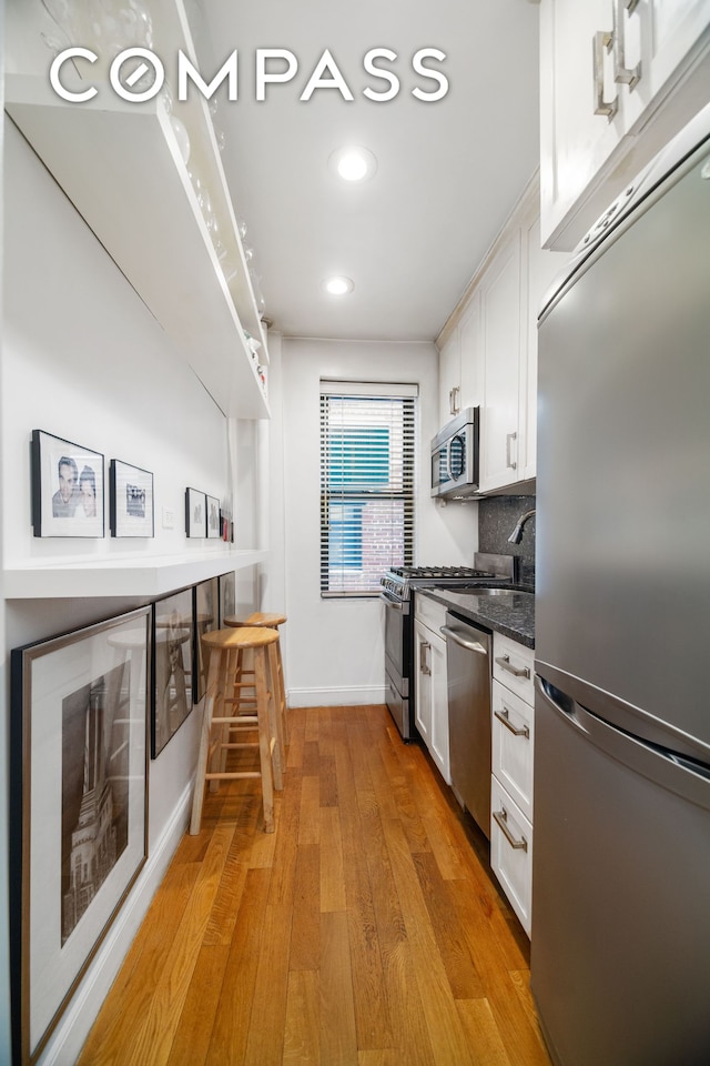 kitchen with recessed lighting, white cabinets, light wood-style flooring, backsplash, and stainless steel appliances