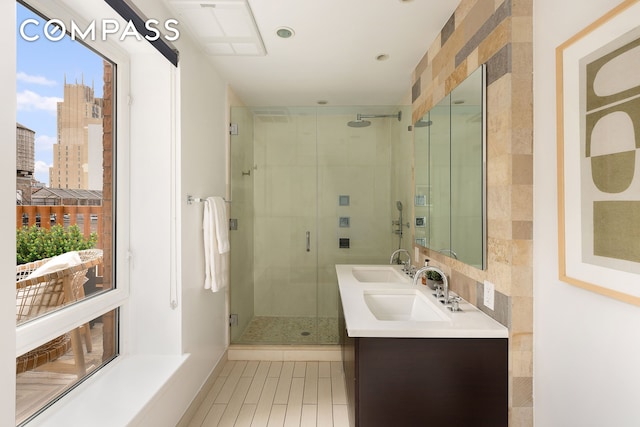 bathroom with double vanity, a sink, tile patterned flooring, and a stall shower
